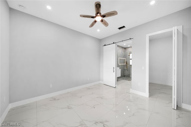 unfurnished bedroom featuring a barn door, ceiling fan, light tile floors, and connected bathroom