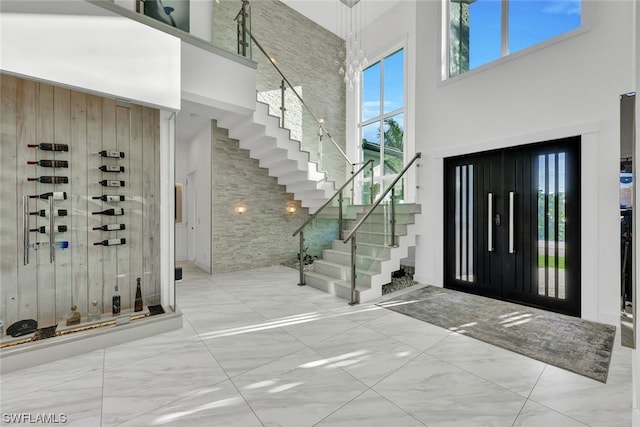 foyer entrance featuring a towering ceiling and wood walls