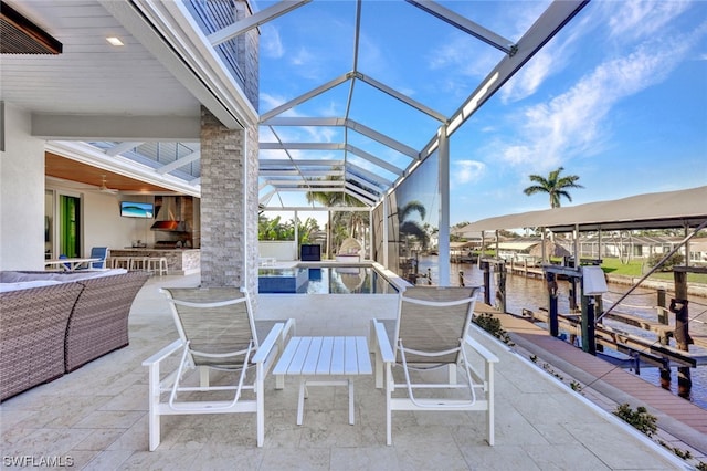 view of patio / terrace featuring a dock, ceiling fan, and glass enclosure