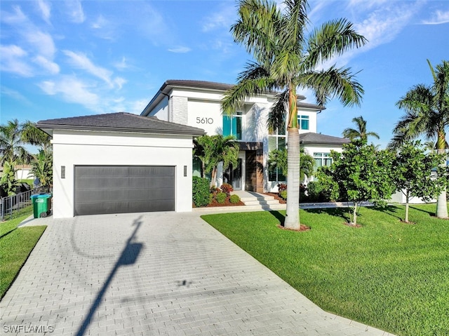 view of front of house featuring an attached garage, a front lawn, decorative driveway, and stucco siding