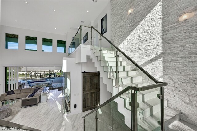 stairway featuring a towering ceiling and a barn door