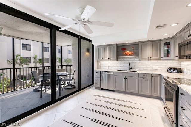 kitchen with ceiling fan, light tile floors, light stone counters, backsplash, and stainless steel appliances