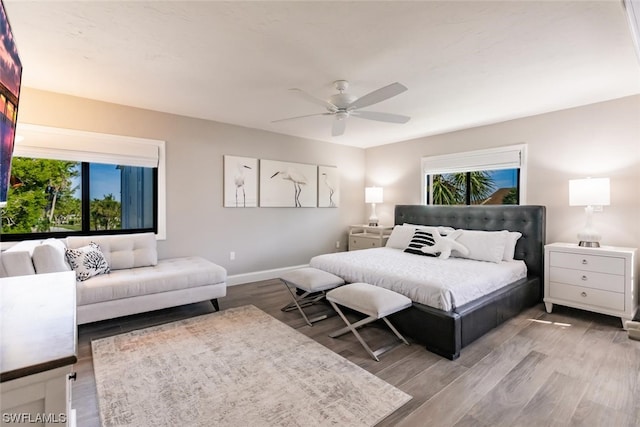 bedroom featuring ceiling fan, multiple windows, and wood-type flooring