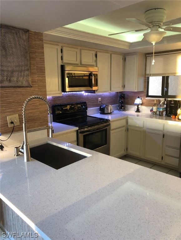 kitchen featuring ceiling fan, sink, range with electric stovetop, cream cabinets, and tasteful backsplash