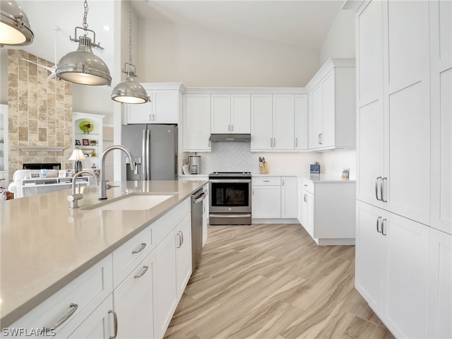 kitchen featuring white cabinets, vaulted ceiling, hanging light fixtures, stainless steel appliances, and backsplash