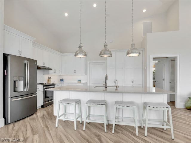 kitchen featuring an island with sink, white cabinets, high vaulted ceiling, stainless steel appliances, and sink