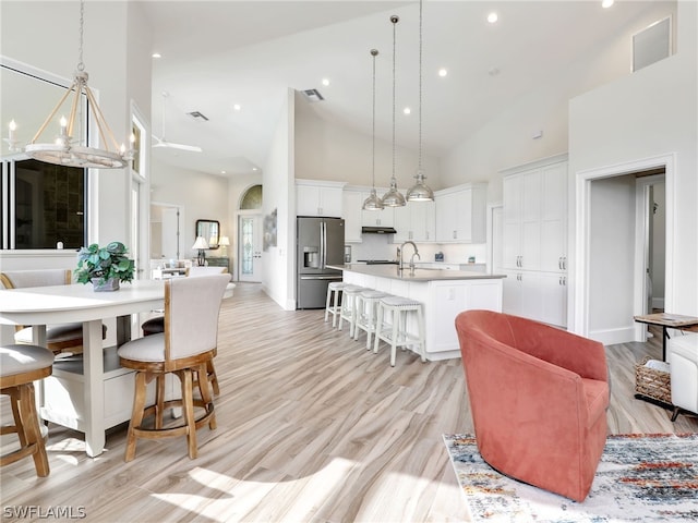 interior space featuring high vaulted ceiling, light wood-type flooring, a notable chandelier, and sink