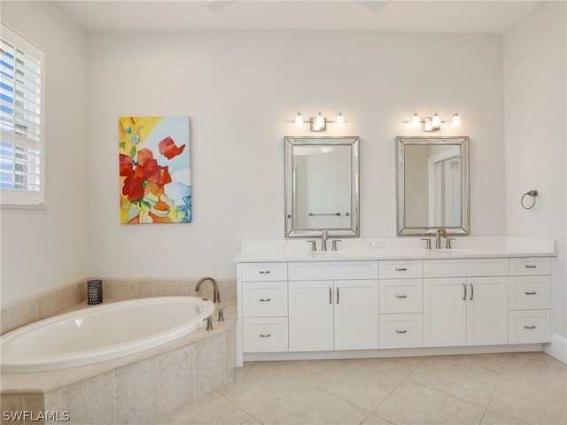 bathroom featuring tiled tub, vanity, and tile patterned flooring