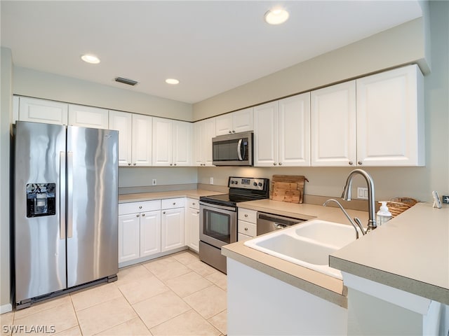 kitchen featuring white cabinets, light tile flooring, stainless steel appliances, and kitchen peninsula