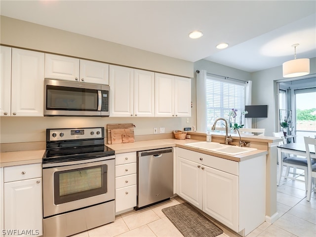 kitchen with appliances with stainless steel finishes, white cabinetry, kitchen peninsula, and sink