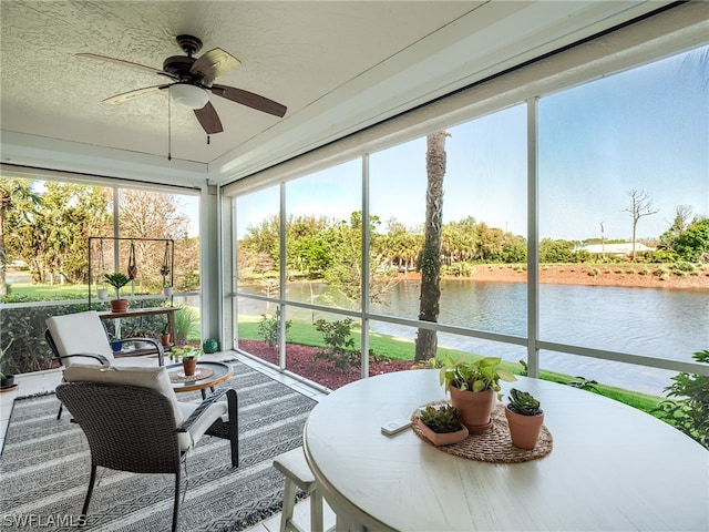 sunroom with a water view and ceiling fan