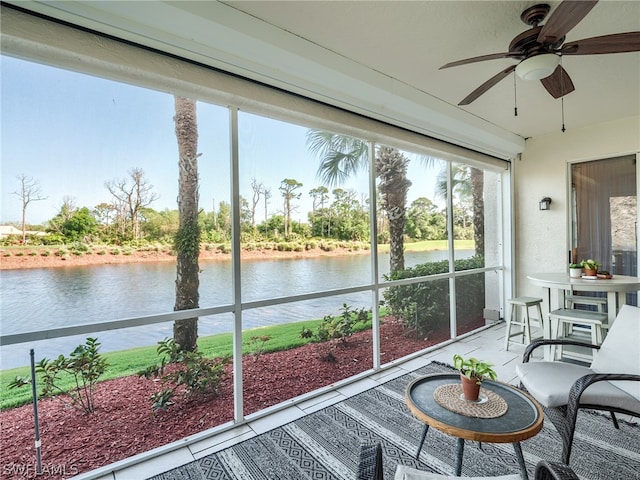 sunroom featuring ceiling fan and a water view