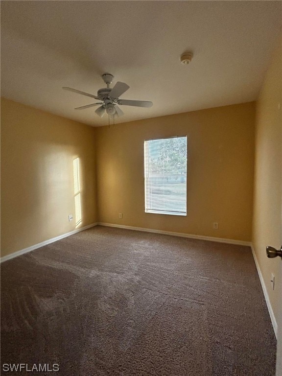 unfurnished room with ceiling fan and dark colored carpet