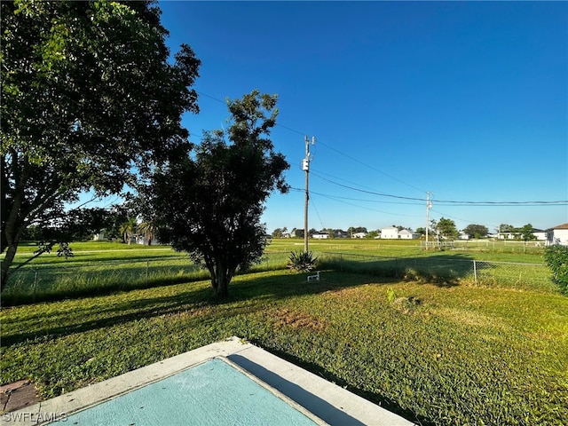 view of swimming pool with a rural view and a yard