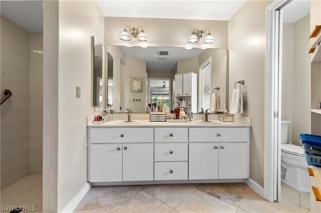 bathroom with vanity, toilet, and tiled shower