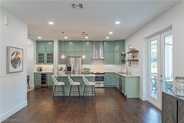 kitchen with dark hardwood / wood-style floors, pendant lighting, sink, appliances with stainless steel finishes, and wall chimney range hood