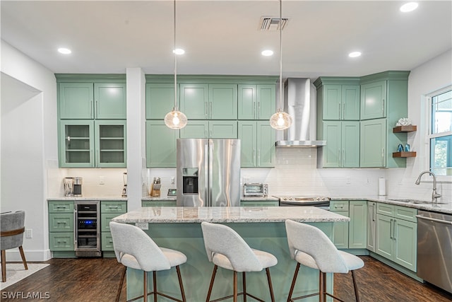 kitchen with pendant lighting, dark wood-type flooring, appliances with stainless steel finishes, and wall chimney range hood