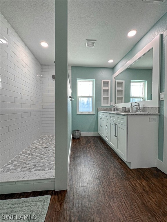 bathroom with wood-type flooring, a healthy amount of sunlight, a textured ceiling, and vanity