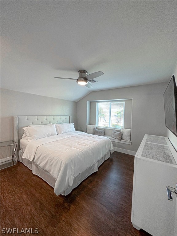 bedroom featuring ceiling fan, lofted ceiling, a textured ceiling, and dark wood-type flooring