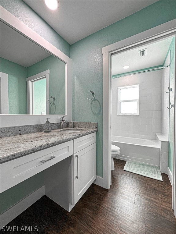 full bathroom featuring tiled shower / bath, toilet, vanity, and wood-type flooring