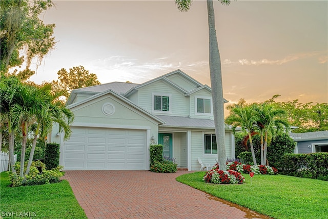 view of front of property featuring a garage and a lawn