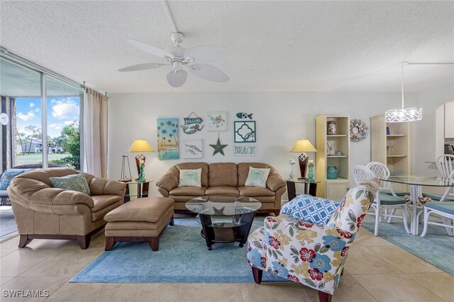 living area featuring a textured ceiling, ceiling fan, expansive windows, and light tile patterned flooring