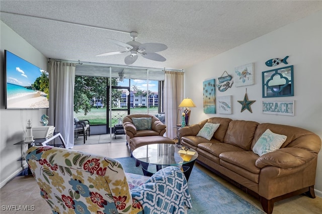 living area featuring a textured ceiling, light tile patterned floors, a ceiling fan, baseboards, and a wall of windows