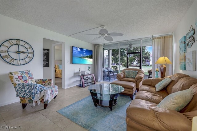 tiled living room featuring ceiling fan, a textured ceiling, and floor to ceiling windows