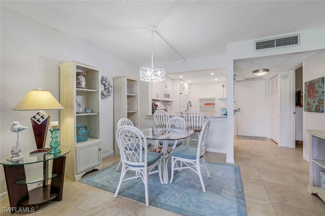 dining space featuring light tile patterned floors, visible vents, and a textured ceiling