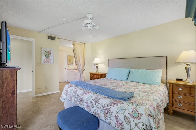 tiled bedroom with baseboards, visible vents, ensuite bath, ceiling fan, and a textured ceiling