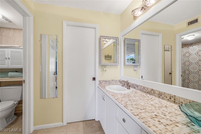 bathroom featuring toilet, vanity, visible vents, and tile patterned floors