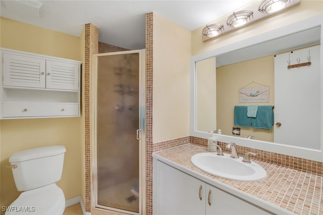 bathroom with toilet, a stall shower, and vanity