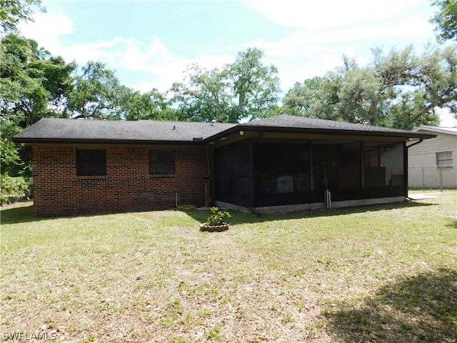 back of property with a sunroom and a lawn