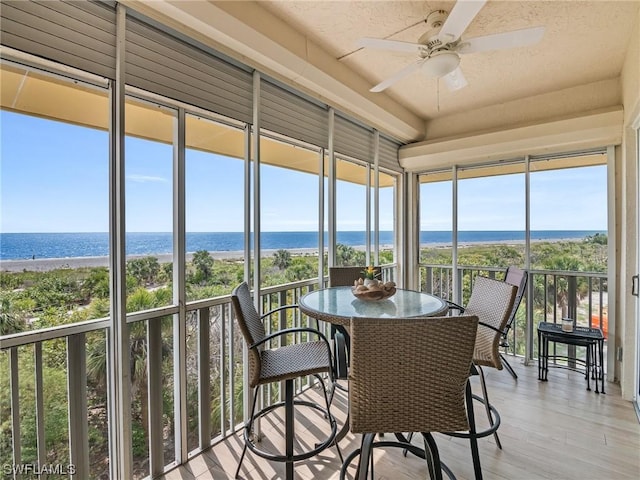 sunroom / solarium with ceiling fan and a water view