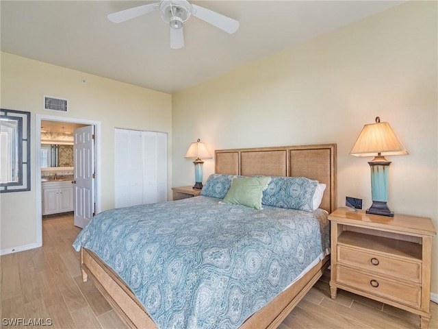 bedroom with light wood finished floors, a closet, visible vents, ensuite bathroom, and baseboards