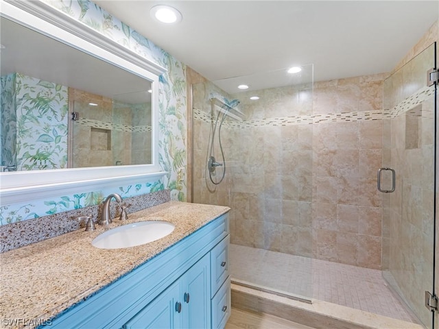 full bathroom with recessed lighting, wallpapered walls, a shower stall, and vanity