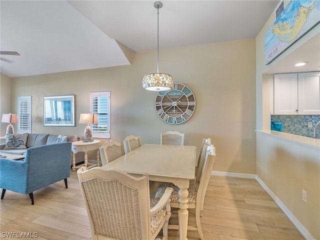 dining space featuring baseboards, ceiling fan, and light wood finished floors