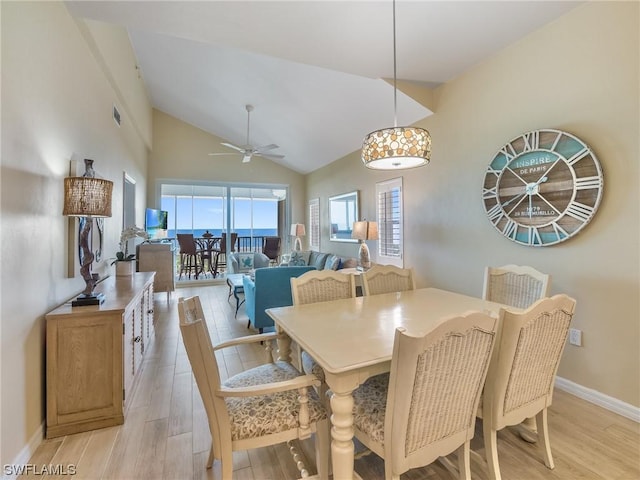 dining area featuring a ceiling fan, baseboards, high vaulted ceiling, and light wood finished floors