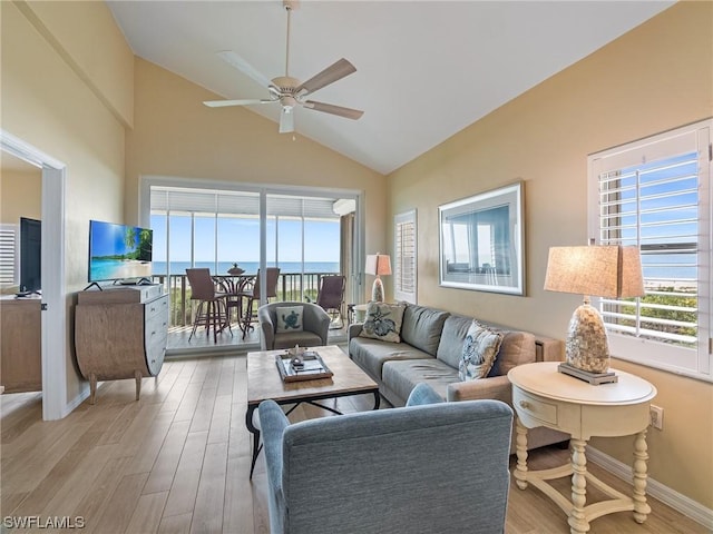 living area featuring baseboards, high vaulted ceiling, a ceiling fan, and light wood-style floors