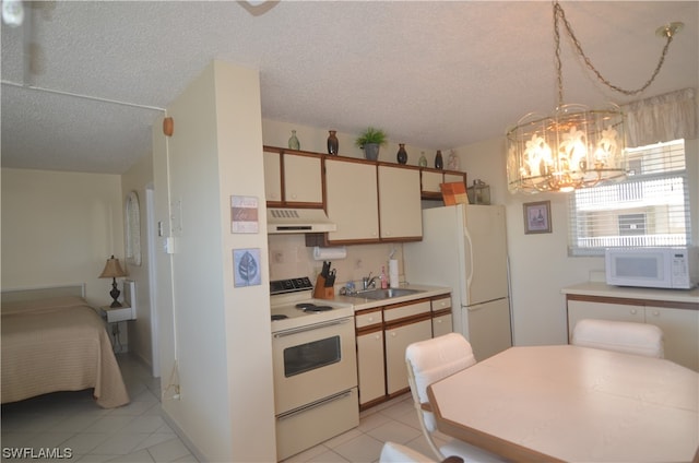 kitchen featuring white appliances, a textured ceiling, sink, an inviting chandelier, and light tile floors