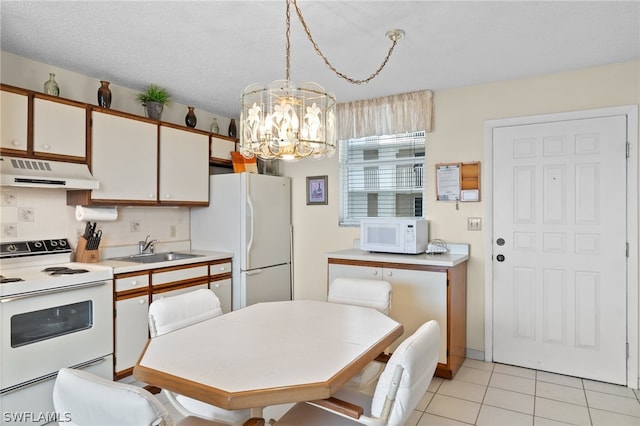 kitchen with hanging light fixtures, white appliances, light tile flooring, white cabinetry, and sink