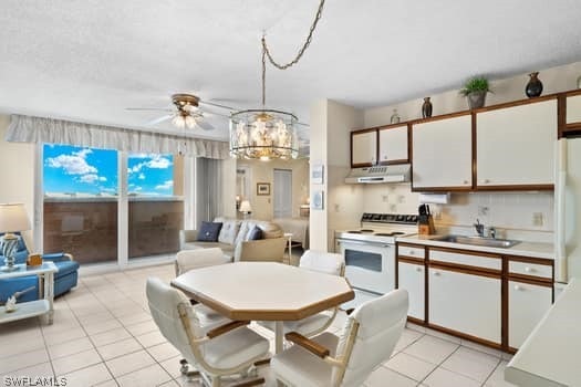 tiled dining room featuring ceiling fan with notable chandelier and sink