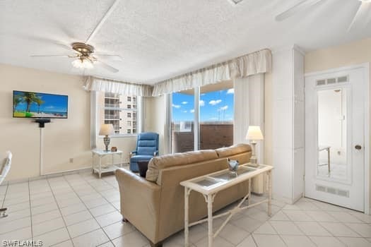 tiled living room with ceiling fan and a textured ceiling