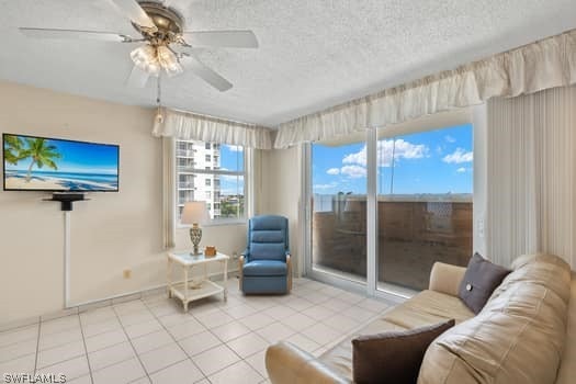 living room featuring a textured ceiling, ceiling fan, and tile floors