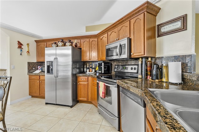 kitchen featuring backsplash, appliances with stainless steel finishes, sink, light tile floors, and dark stone counters