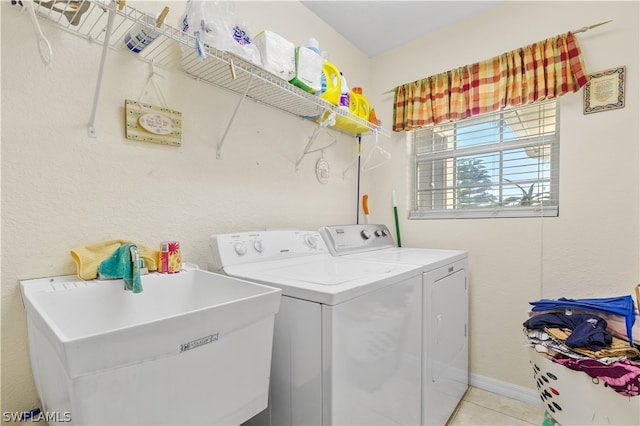 laundry area featuring washer and clothes dryer, light tile flooring, and sink