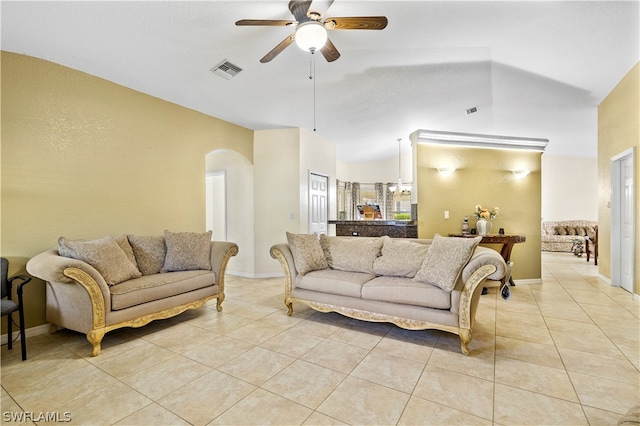 tiled living room with ceiling fan with notable chandelier and vaulted ceiling