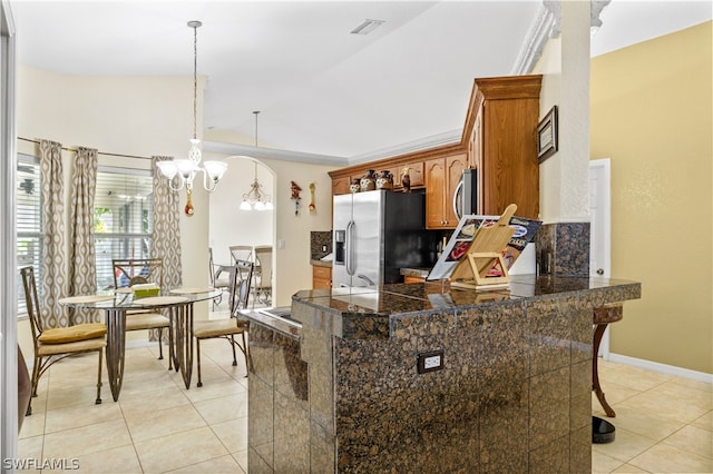 kitchen featuring pendant lighting, light tile floors, a notable chandelier, kitchen peninsula, and appliances with stainless steel finishes