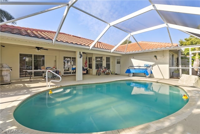 view of swimming pool with a patio, area for grilling, ceiling fan, and glass enclosure