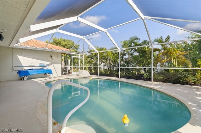 view of swimming pool featuring glass enclosure and a patio area